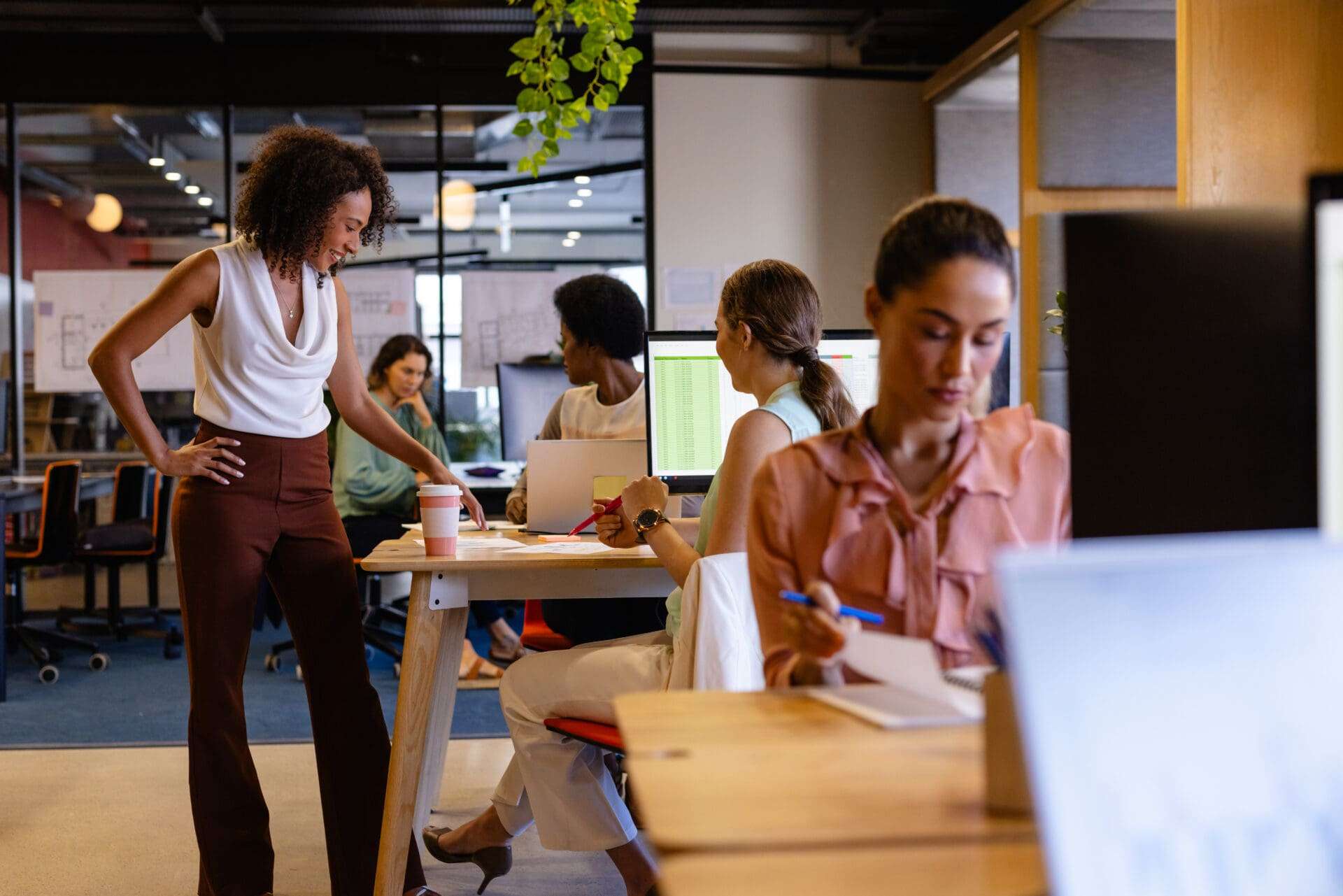 Female colleagues in discussion in hot desking office.