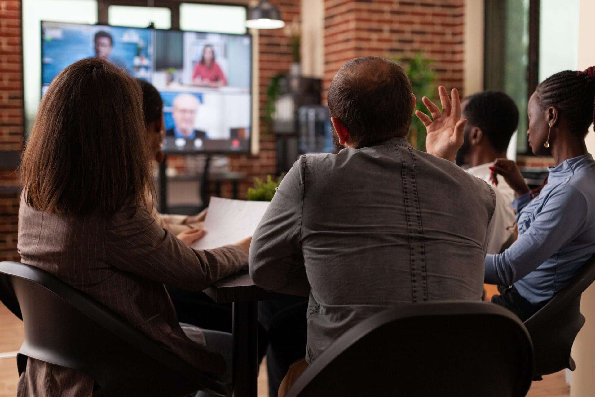 Group of diverse team working at company collaboration discussing strategy ideas with remote executives managers during online videocall meeting in startup office. Business call conference on monitor