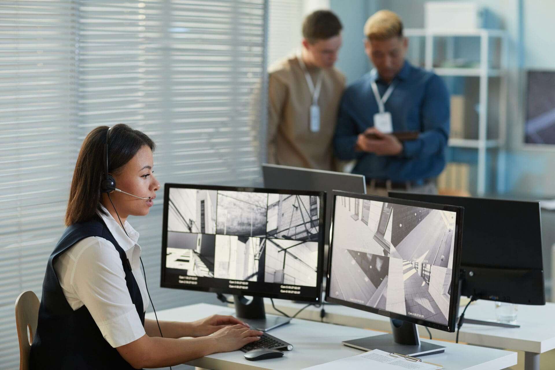 Side view portrait of young woman wearing headset while watching surveillance camera feed in security and monitoring office, copy space