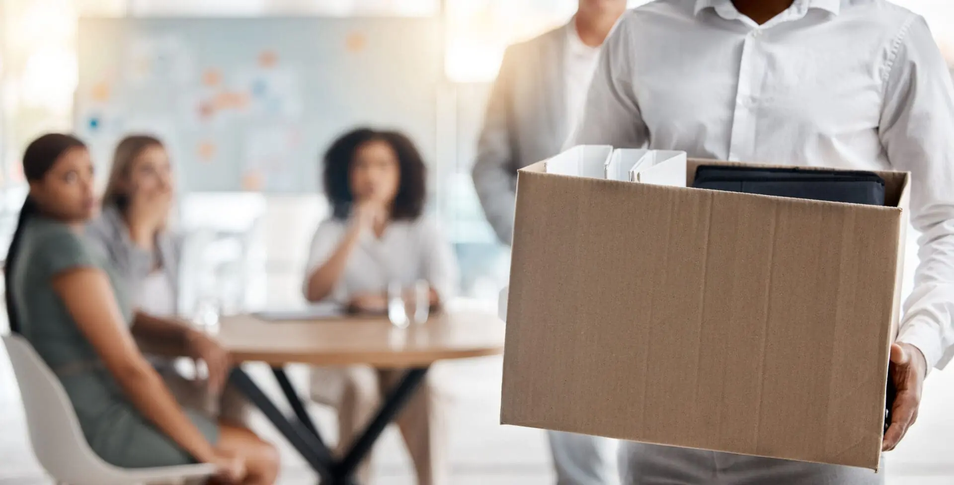 Business man carries a box of his belongings out of the office.